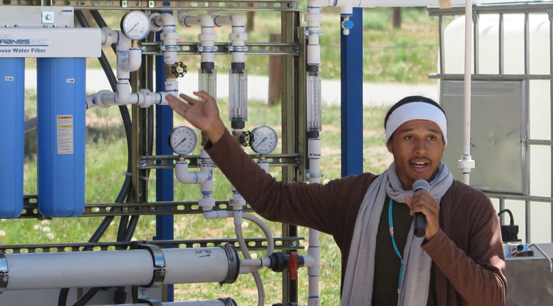 Man speaking in front of a water filtration station