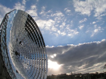 Solar dish pointing to a cloudy and blue sky.