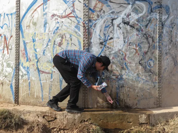 Chris Yazzie from Indige-FEWSS testing water next to a water tank