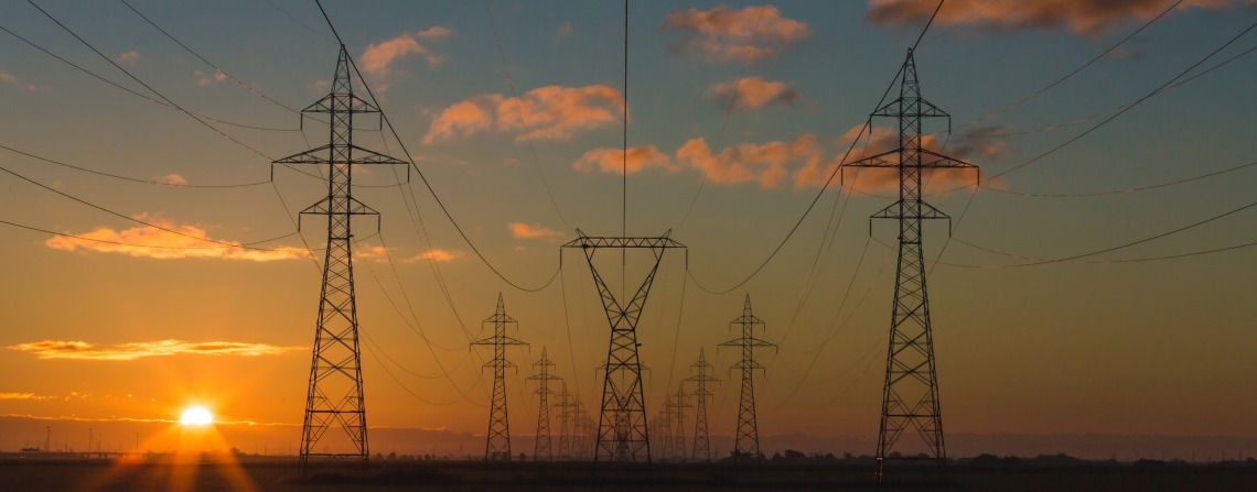 Power line towers at sunset under a hazy sky