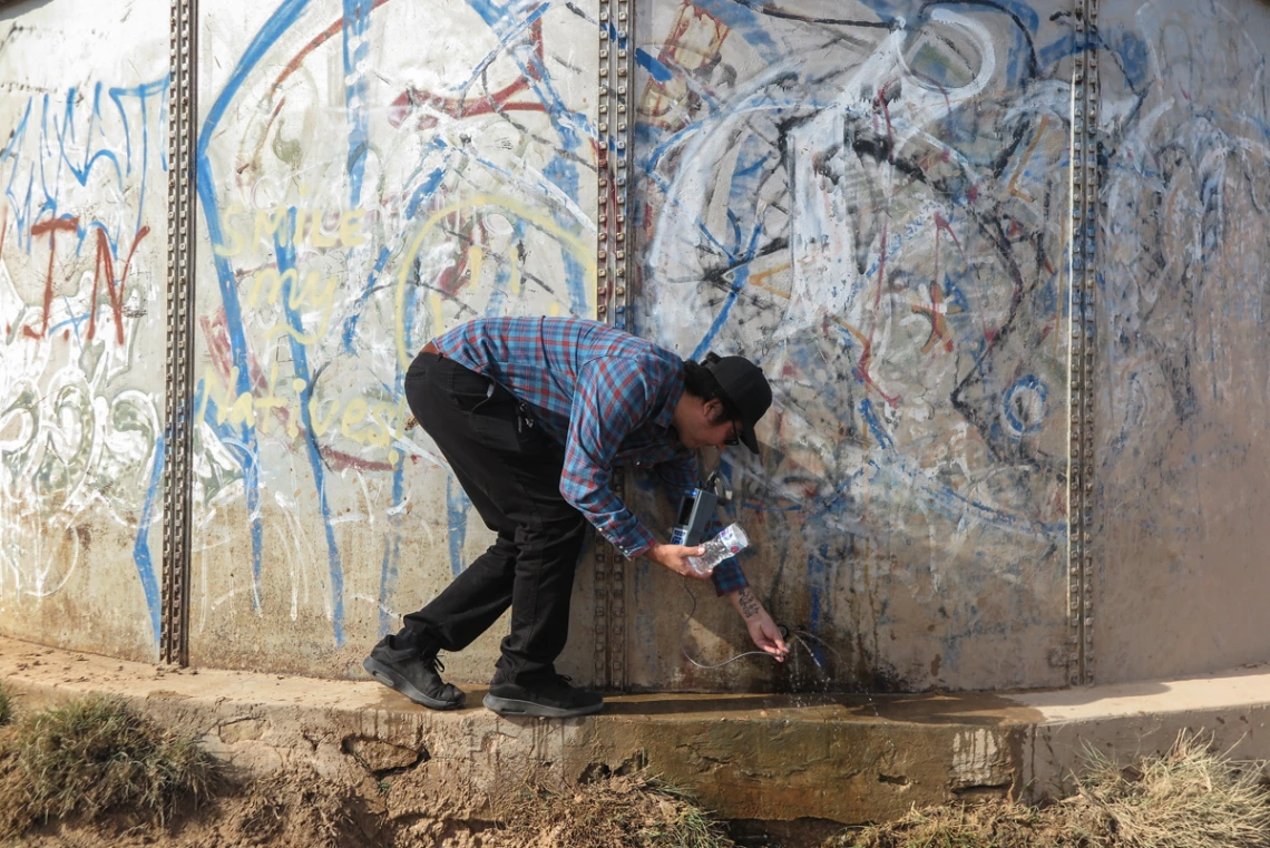 Chris Yazzie from Indige-FEWSS testing water next to a water tank